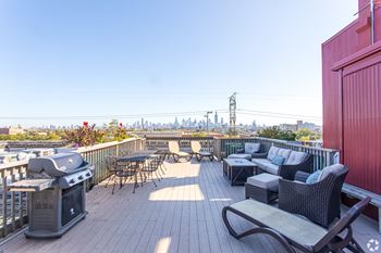 a rooftop deck with furniture and a city in the background